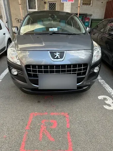 Peugeot gri în parcare, vedere din față a farurilor