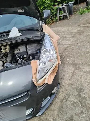 Far cu lentila clară, mascat cu hârtie, pe o mașină gri