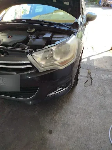 Far îngălbenit pe o mașină închisă la culoare, cu capota deschisă
